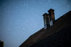 Cette image montre le toit d'une maison avec une cheminée symbolisant l'entretien de cheminée grâce au ramonage.